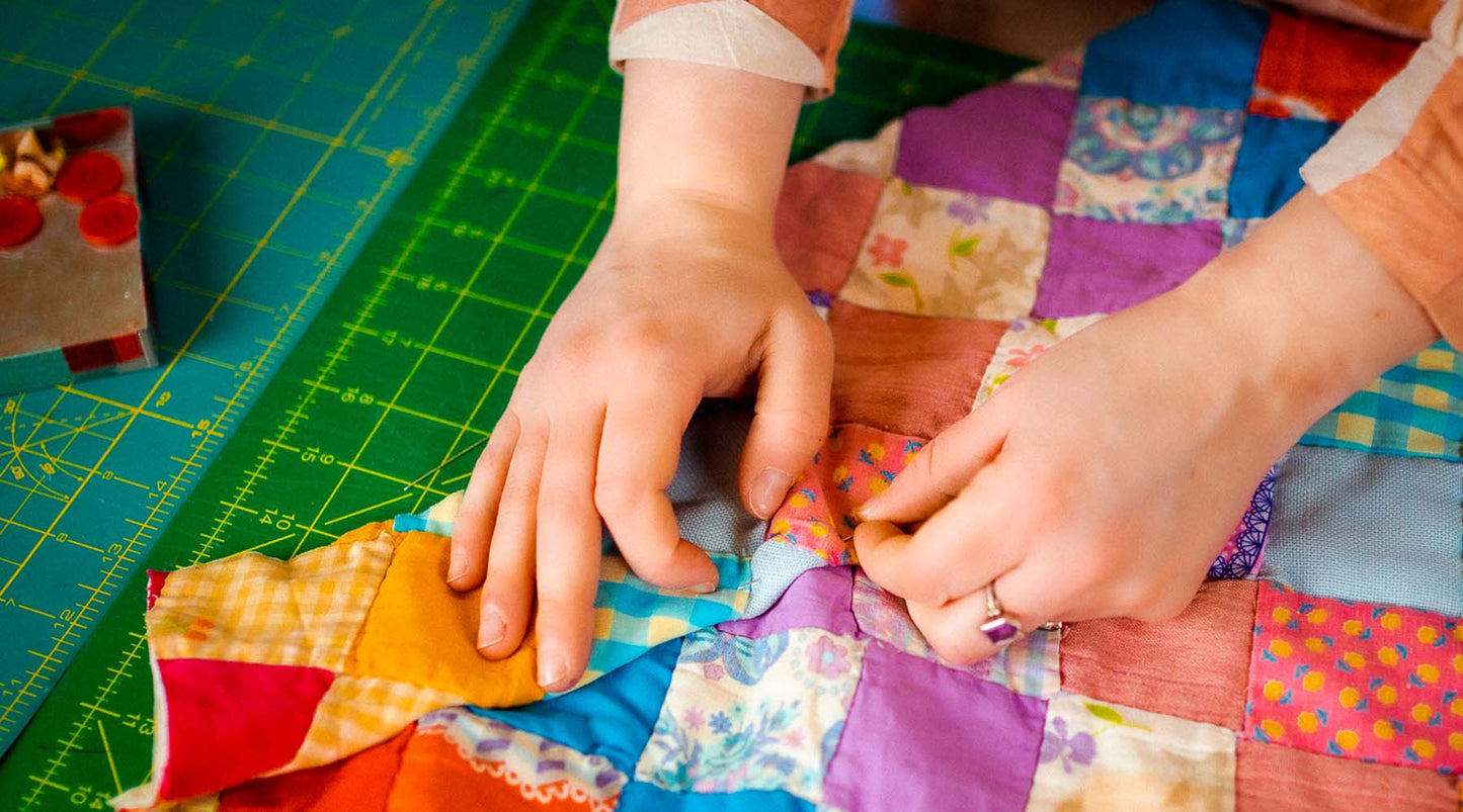close up of hands preparing a quilt to sewn into a jacket